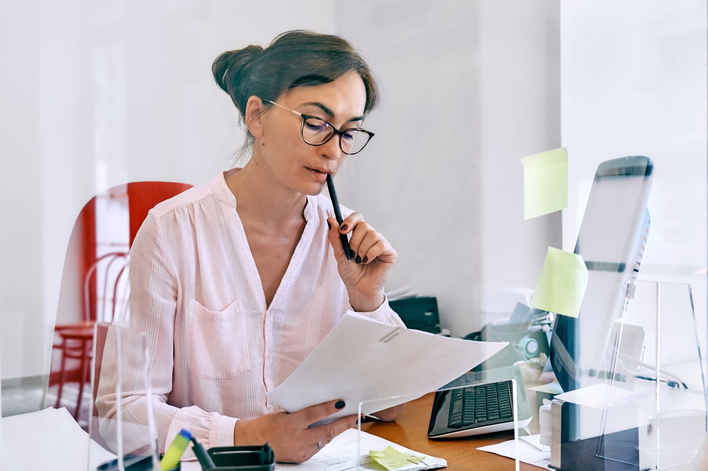 Attentive Female Bookkeeper Check Accounts Bills. Middle Aged Woman Social Worker Counting Grant Subsidy Rates, Reviewing The Company's Financial Data At Office Workplace With Plexiglass Separator. - Auster Inteligência Contábil