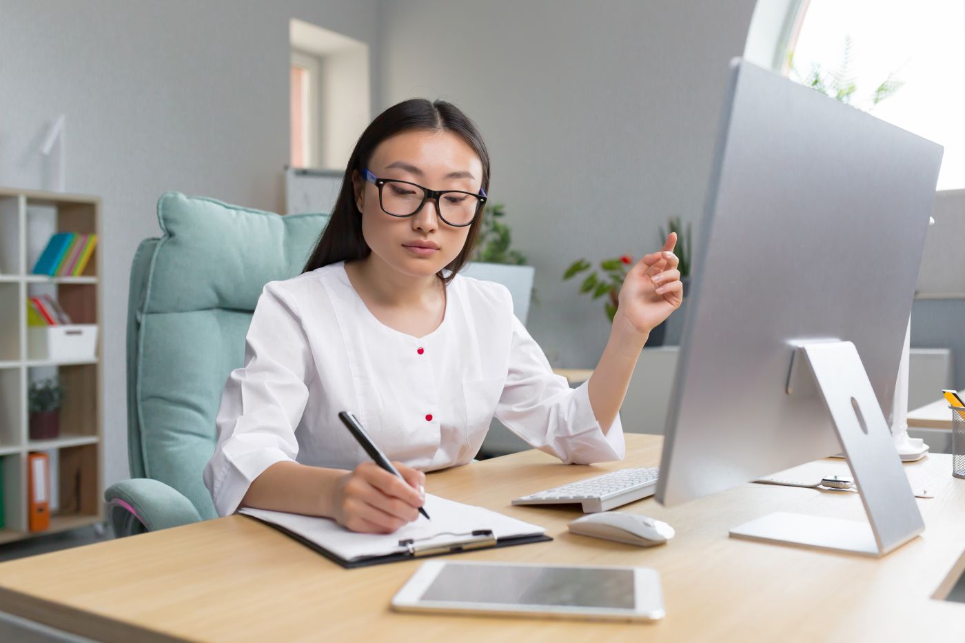 The Work Of A Doctor. Young Beautiful Asian Woman Doctor In Glasses And Medical Gown In The Office - Auster Inteligência Contábil
