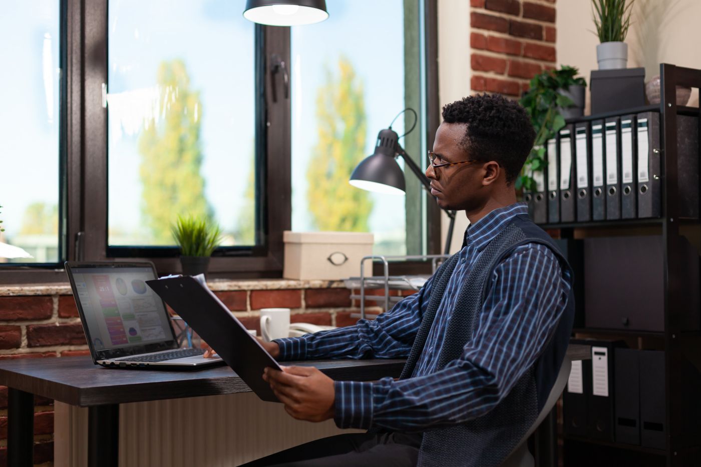 Empreendedor Olhando Para A Tela Do Laptop Com Resultados De Vendas Segurando Uma Prancheta Com Graficos De Negocios Min - Auster Inteligência Contábil