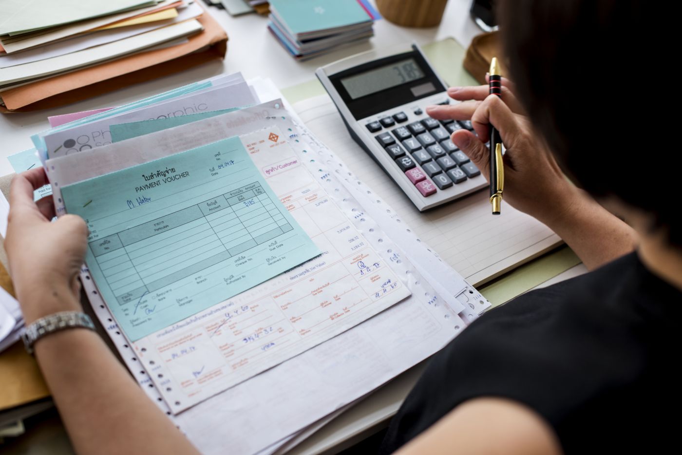 Asian Woman Working Through Paperwork - Auster Inteligência Contábil