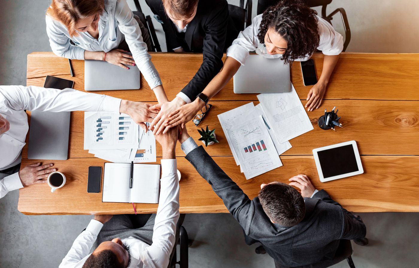 Business People Holding Hands Together During Meeting Sitting In Office - Auster Inteligência Contábil