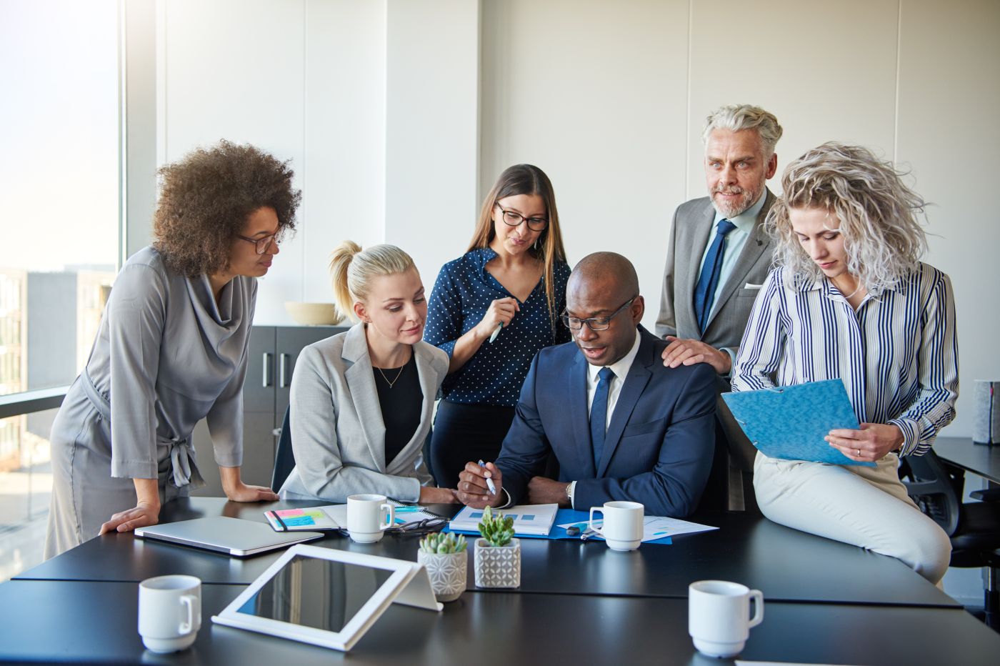 Diverse Group Of Colleagues Discussing Paperwork Together In An Office - Auster Inteligência Contábil